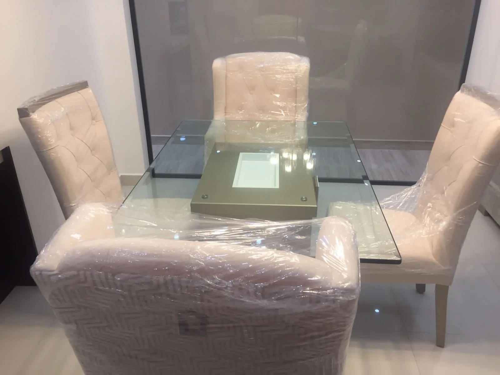 Comedor escena de mudanza/entrega con sillas y sofás envueltos en plástico
