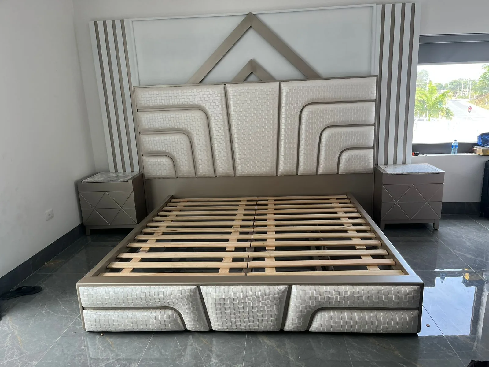 Cabecera de cama con textura tejida en canales curvos y remate metálico triangular (estilo art-decó)