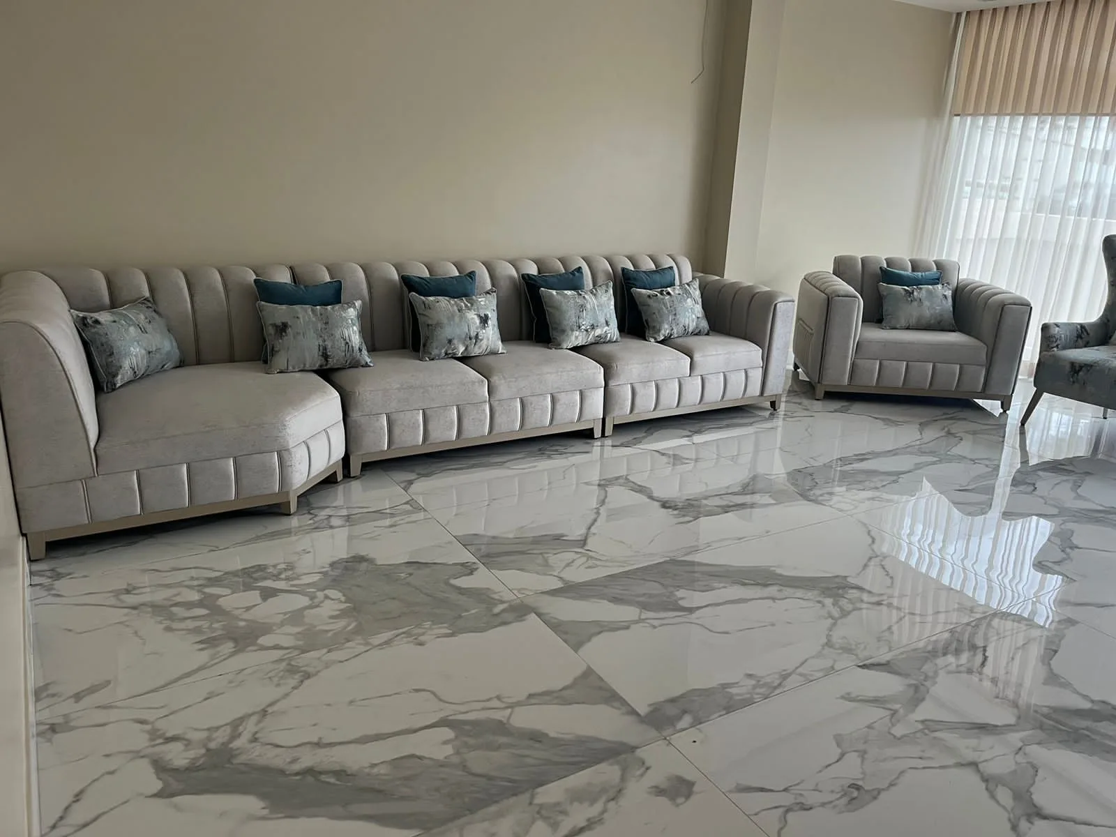 Sala a medida — juego canalado gris con cojines teal, piso mármol