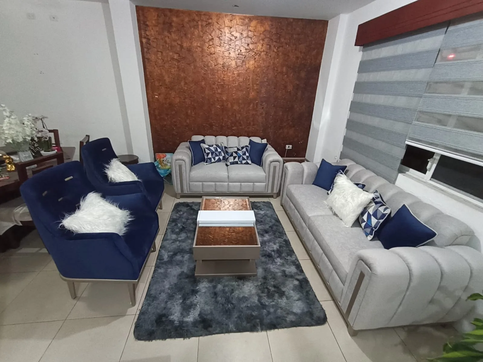 Sala a medida — sofá canalado gris con pared cobre